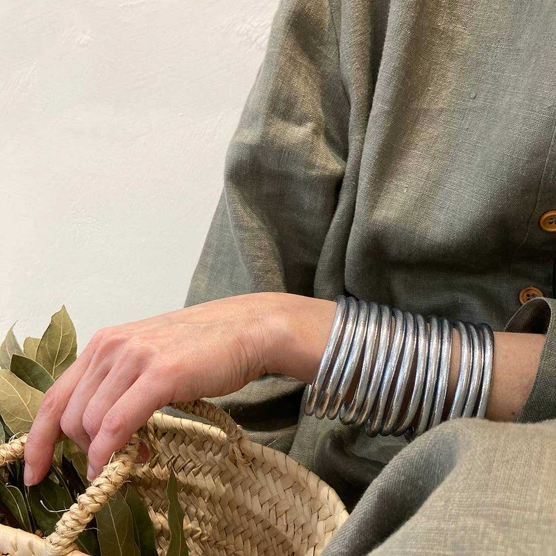 zilveren armband gedragen door een persoon met een grijze jas