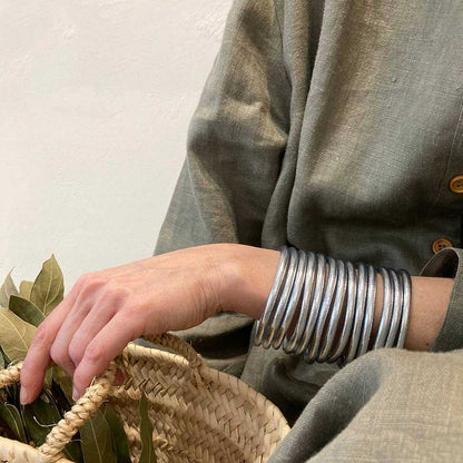 zilveren armband gedragen door een persoon met een grijze jas