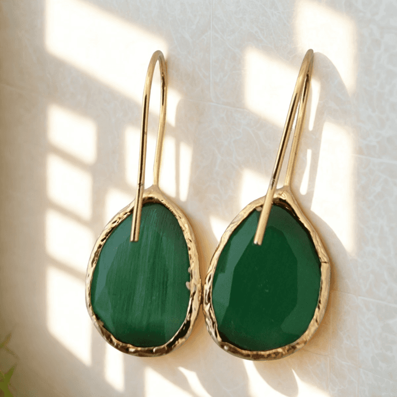 Gouden oorbellen met groene cateye stenen en asymmetrisch ontwerp