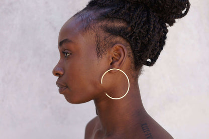 Moedel met unieke messing oorbellen met asymmetrisch design voor een creatieve stijl