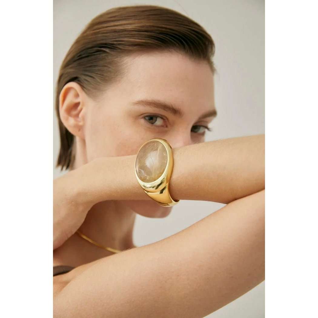 Vrouw draagt vergulde messing armband met goudgerutileerde kwarts, stijlvolle accessoire