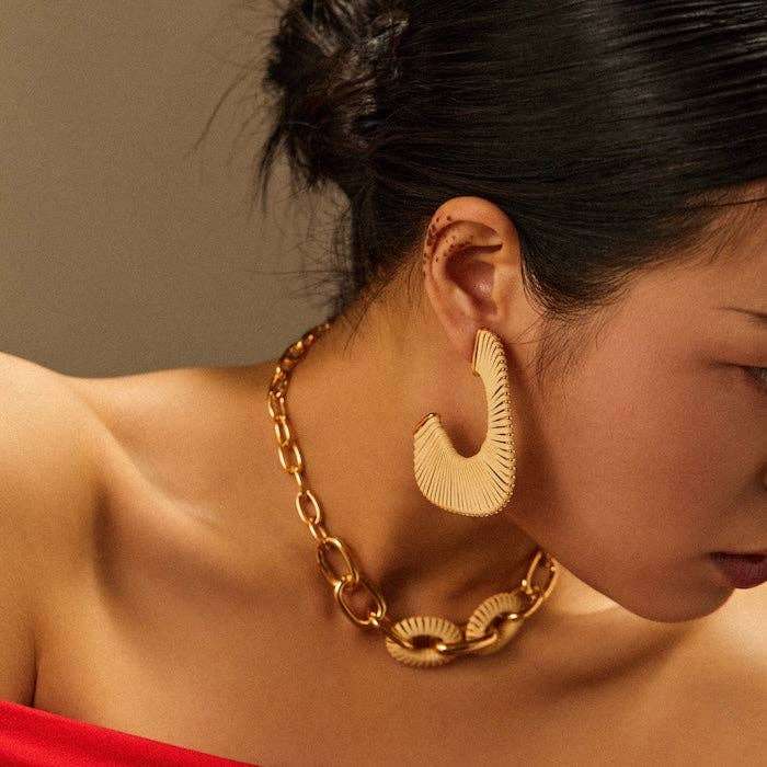 Gouden oorbellen CIRKLA van RAAK.Oorring met ketting