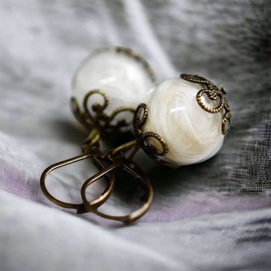 Close-up van handgemaakte glazen bol oorbellen met bronzen decoraties, uniek design