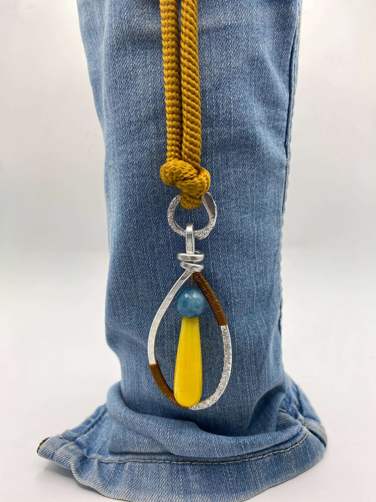 Kleurrijk handgemaakt sieraad met geel en blauwe stenen, gedragen als statement accessoire