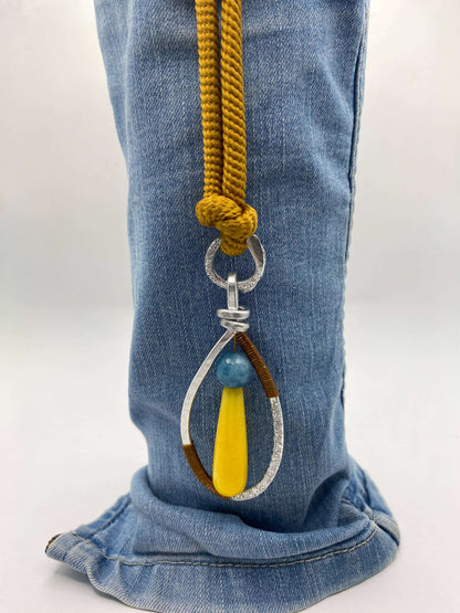 Kleurrijk handgemaakt sieraad met geel en blauwe stenen, gedragen als statement accessoire