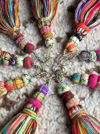 Close-up van kleurrijke vilten kralen en franjes op handgemaakte sleutelhangers, uniek design