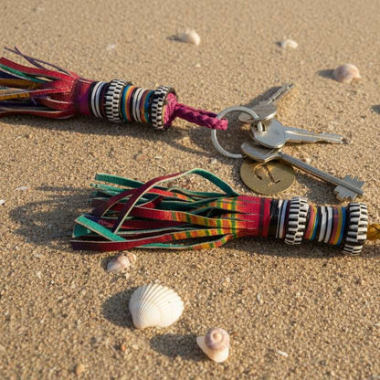 kleurige leren sleutelhanger op zandstrand met schelpen