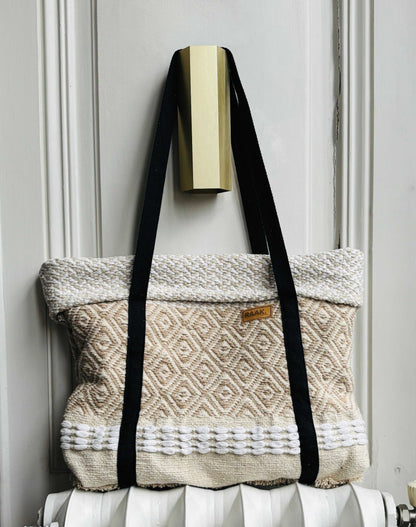 Gerecycleerde beige tas met zwart draagband, hangend aan deurknop